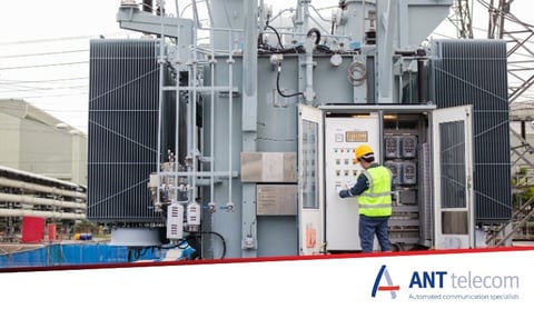 An electrical technician working alone by a huge electrical pylon