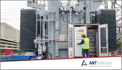 An electrical technician working alone by a huge electrical pylon