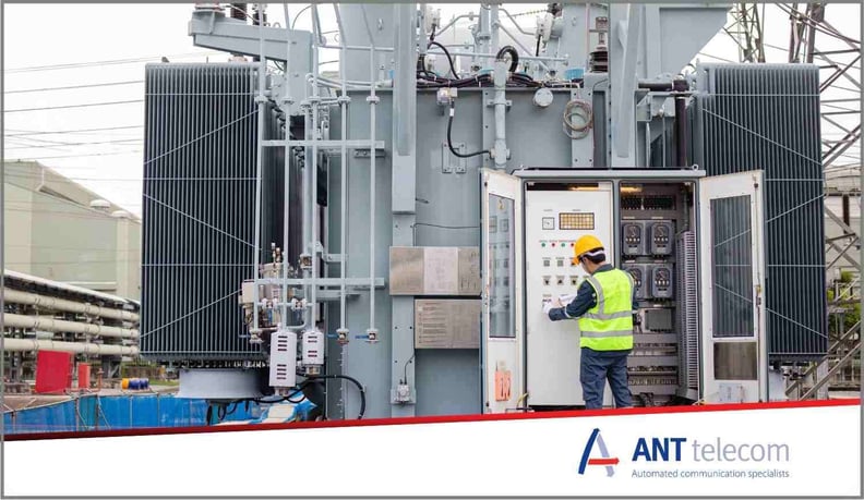 An electrical technician working alone by a huge electrical pylon