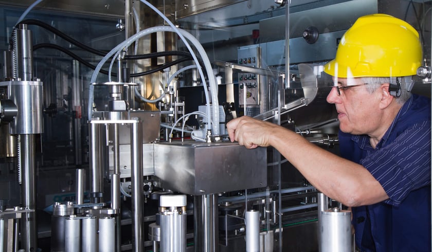 worker in a hard hat inspects machinery